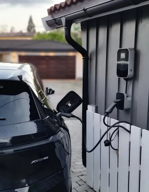 Auto eléctrico cargando junto a una estación de pared en una casa